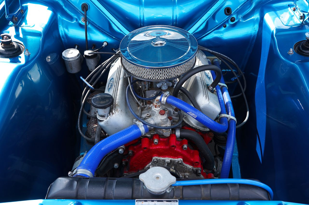 Detailed view of a classic car engine showcasing chrome parts and vibrant blue accents.